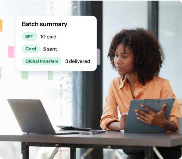 A financial leader sits at her computer. Graphics depict a batch summary from Traild.